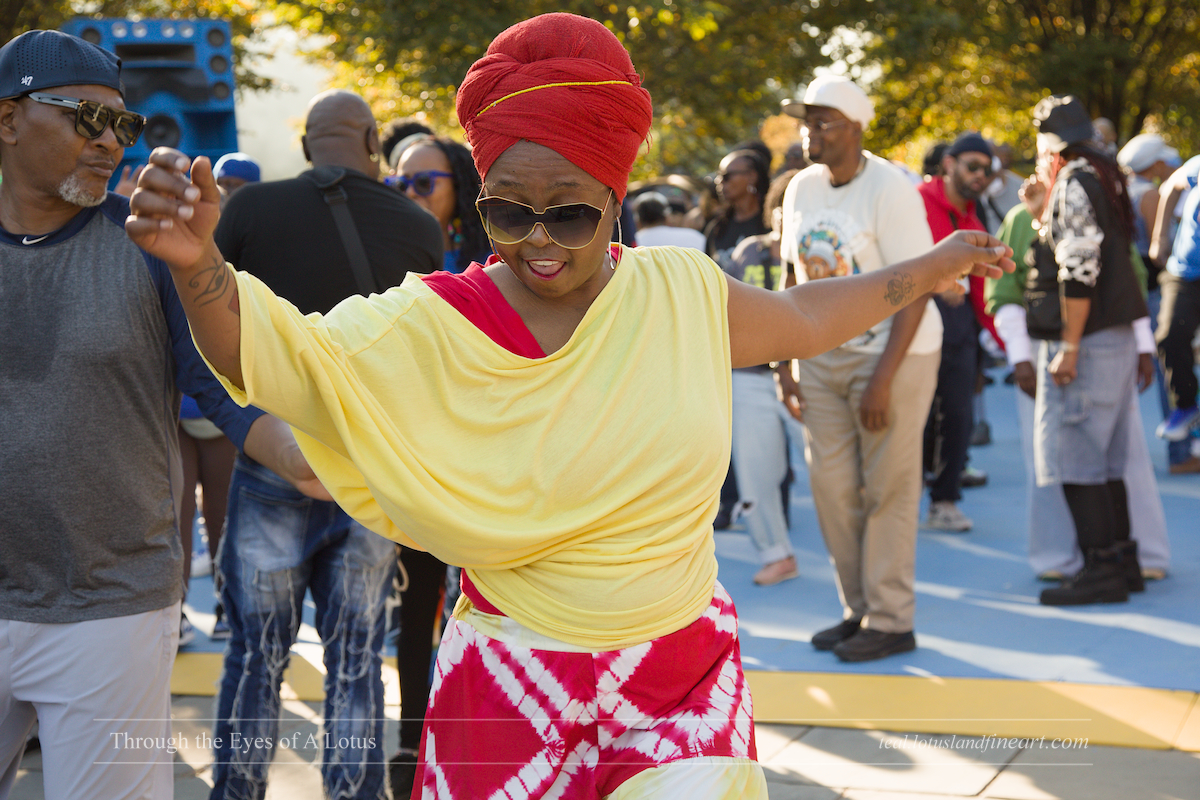A woman in a red head wrap and yellow top dancing at the Ubiquity Soul 2026 Finale in Branch Brook Park